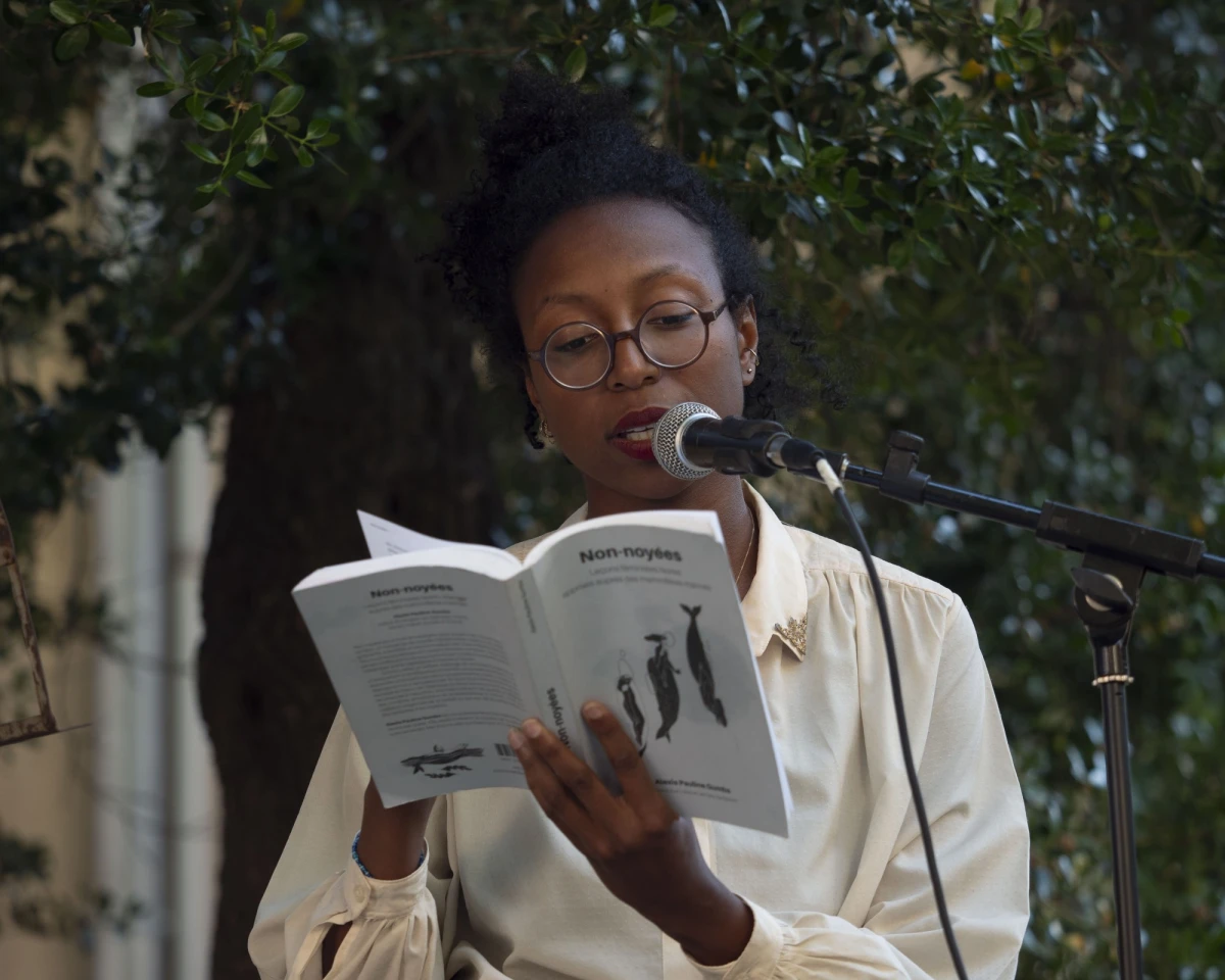 Lecture de “Non-noyées. Leçons féministes Noires apprises auprès des mammifères marines”, collection Burn-Août/Les liens qui libèrent, 2024, par Myriam Rabah-Konaté dans le jardin de la Chapelle Venez. Festival - Lips #2”Hydra”, LABgamerz.<br />
<br />
Crédit photo Louison Vendassi / LABgamerz